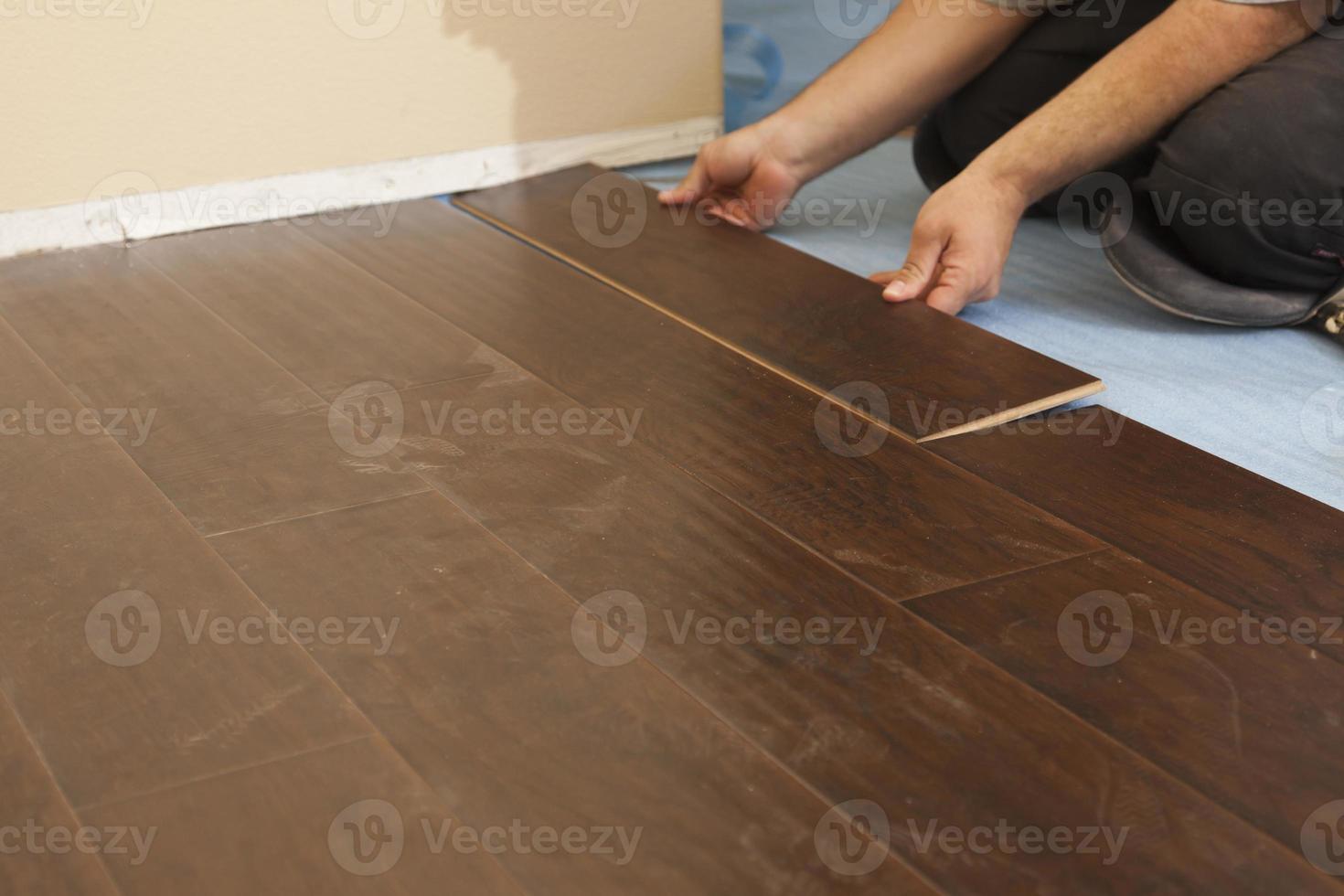 hombre instalando nuevos pisos de madera laminada foto