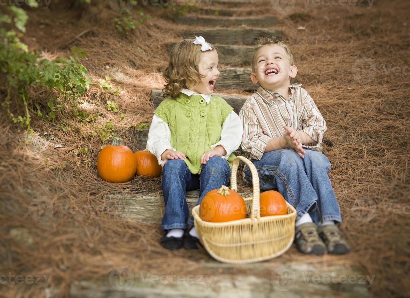 Brother and Sister Children Sitting on Wood Steps with Pumpkins photo