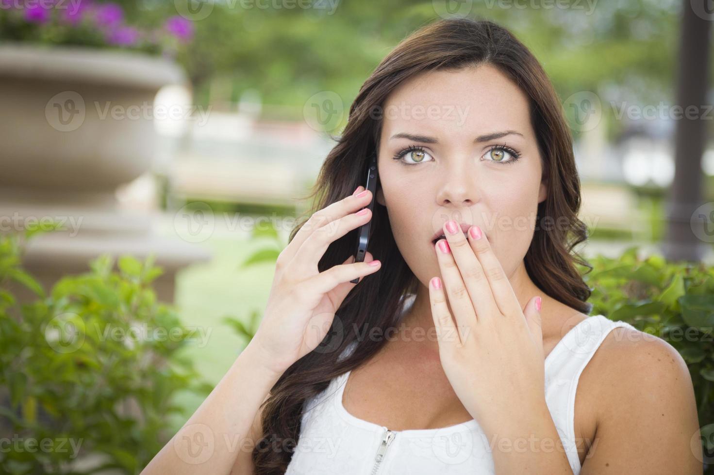 Shocked Young Adult Female Talking on Cell Phone Outdoors photo