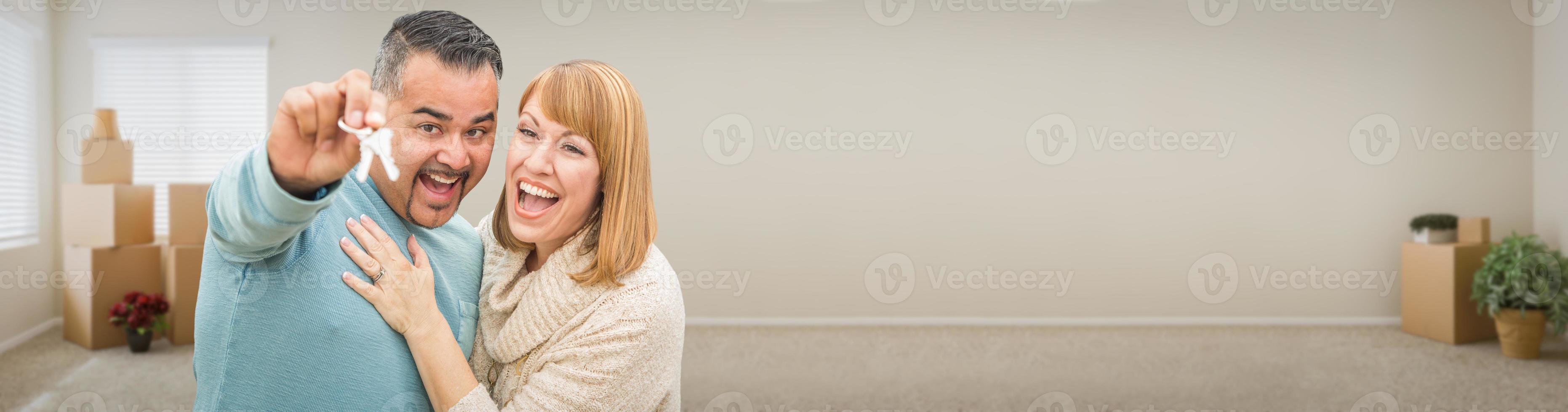 Young Adult Couple Inside Room with Boxes Holding New House Keys Banner. photo