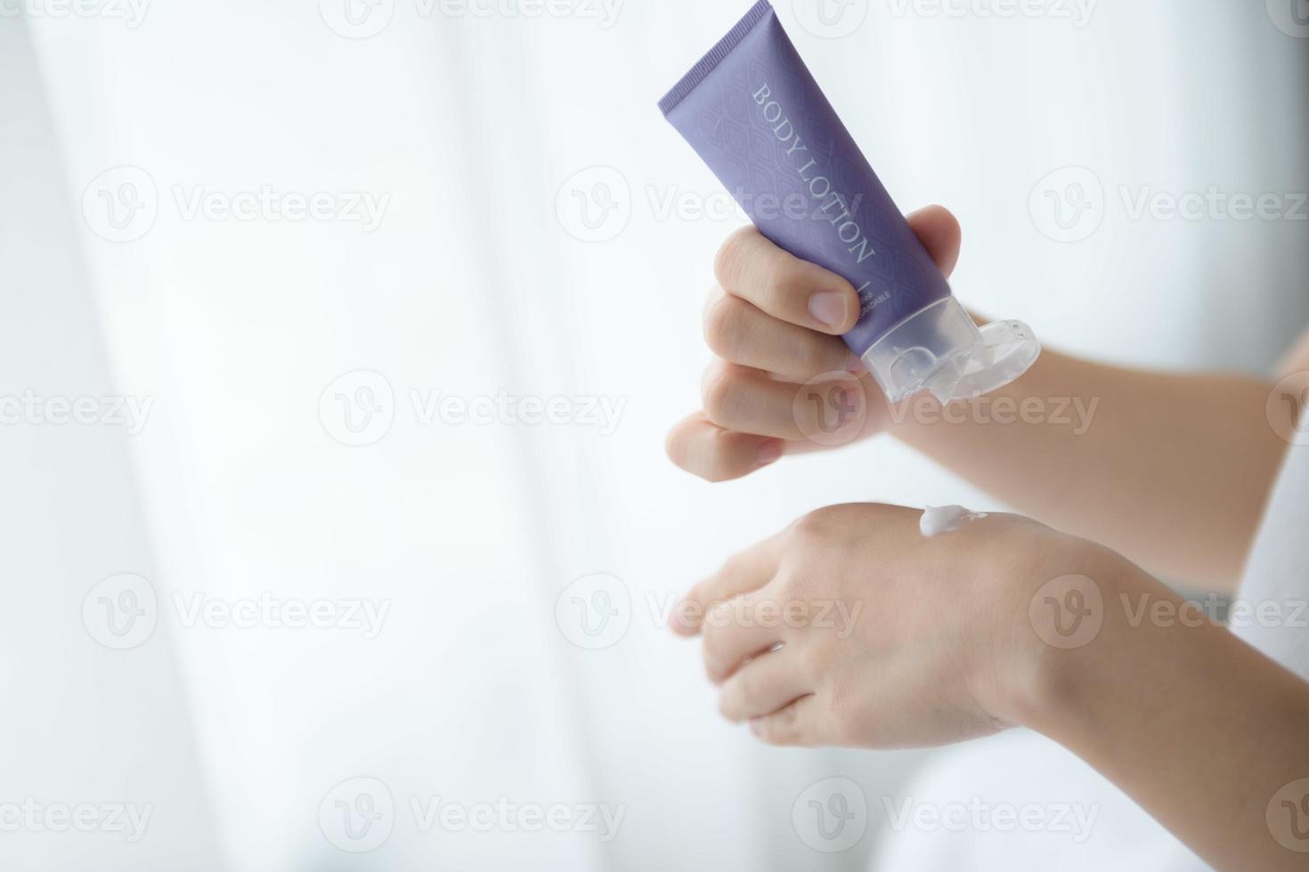 Close up of women applying body lotion cream on hand. photo