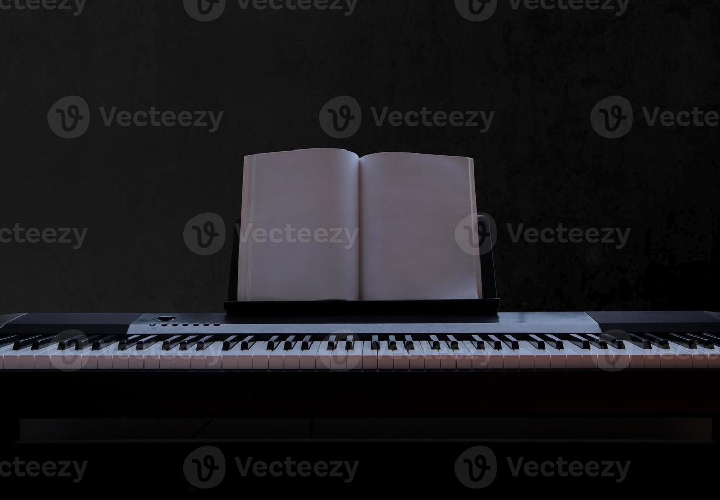Electric piano with empty sheet music on black background, piano keyboard on dark background concept art, front view photo