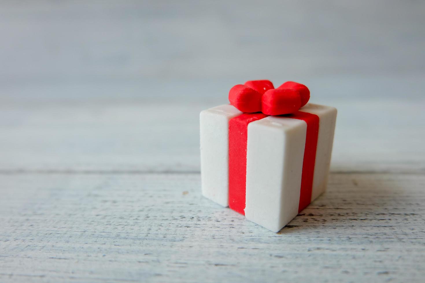 Close up of White gift box with red ribbon on white wooden background for Merry Christmas and happy new year concept. photo