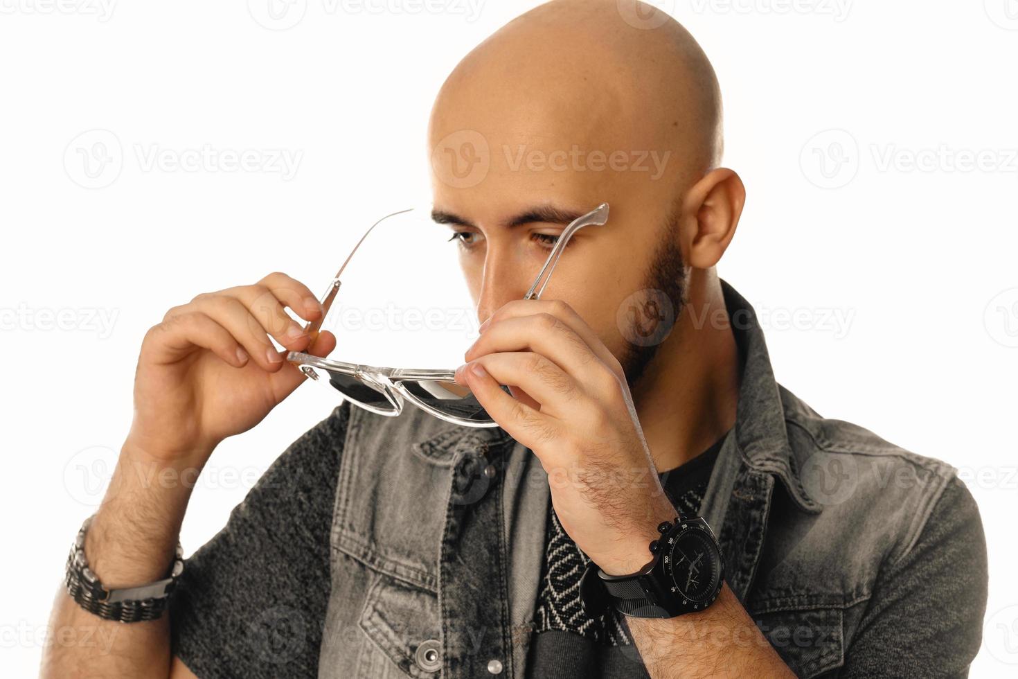 Young handsome man with sunglasses in hands posing in studio photo