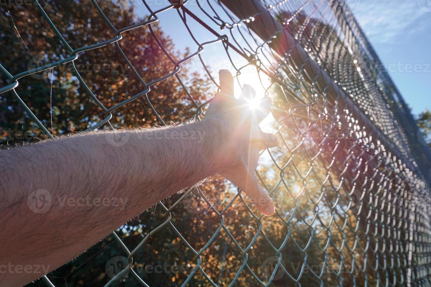 man hand grabbing metallic fence, feeling free photo