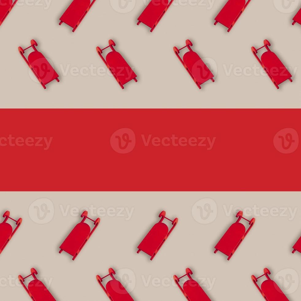 Christmas pattern with red sleighs against beige background . Minimal winter holiday wrap flat lay concept. Red ribbon as a copy space. photo