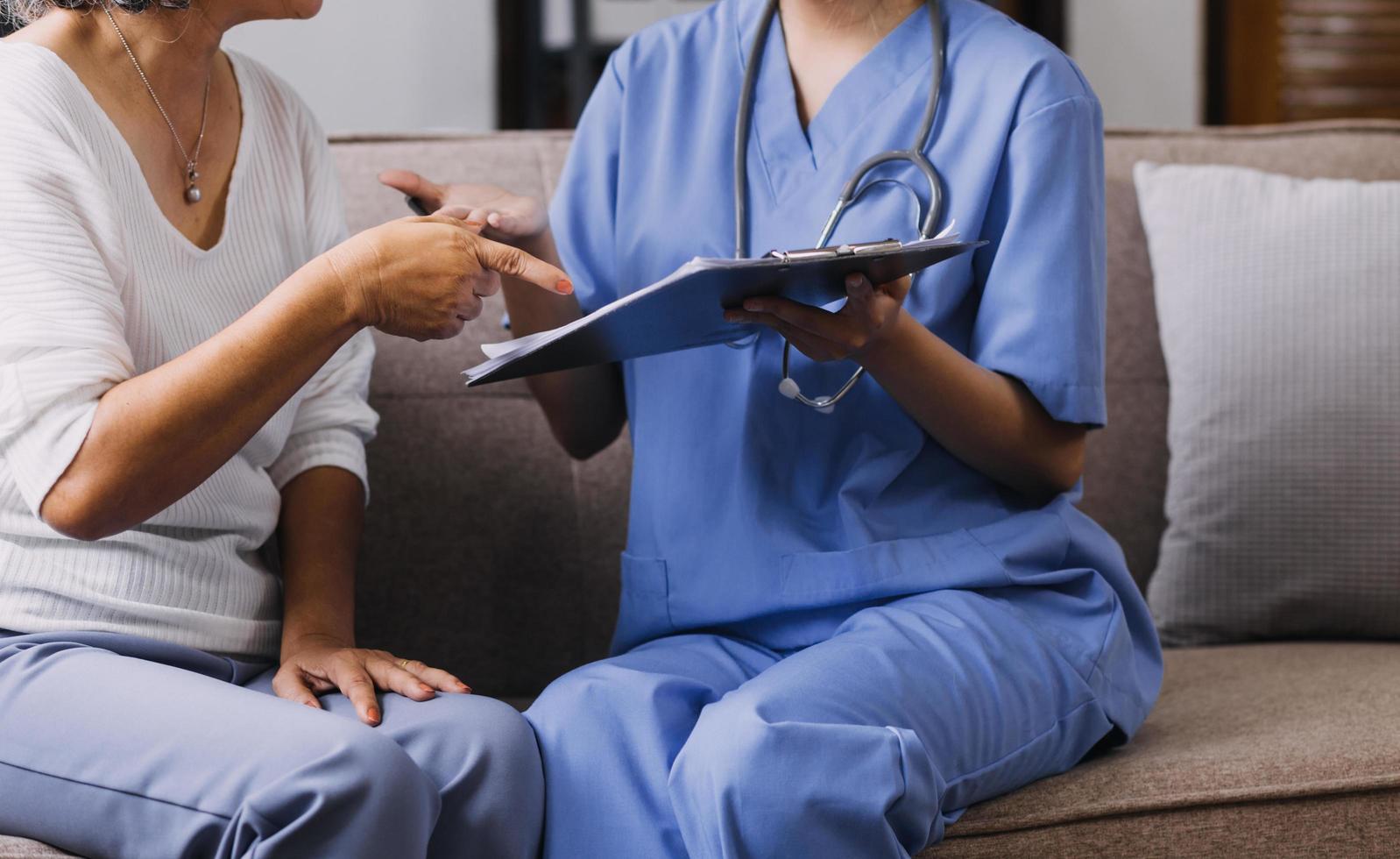 Homecare nursing service and elderly people cardiology healthcare. Close up of young hispanic female doctor nurse check mature caucasian man patient heartbeat using stethoscope during visit photo