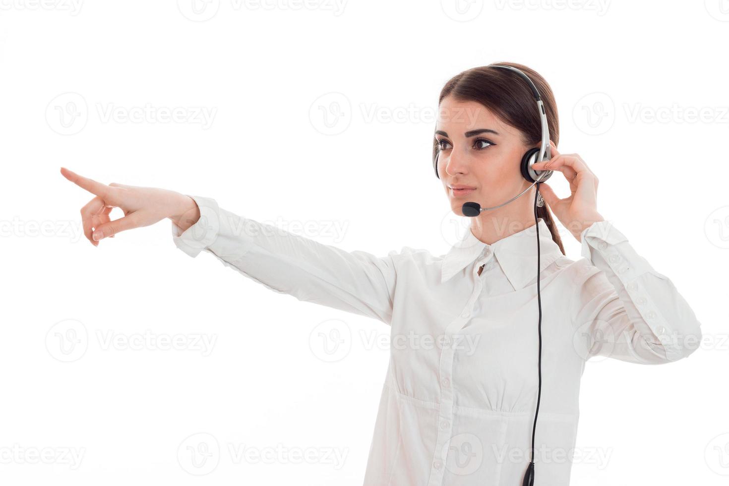 young girl in white shirt stands in headphones and reached out toward photo