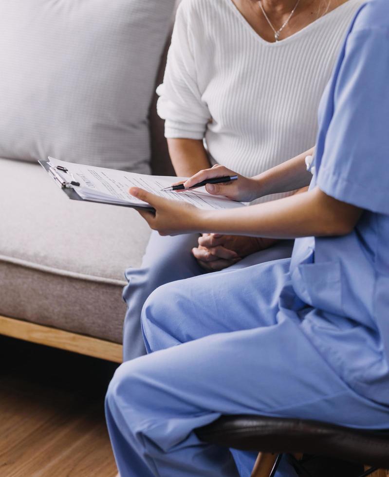 Homecare nursing service and elderly people cardiology healthcare. Close up of young hispanic female doctor nurse check mature caucasian man patient heartbeat using stethoscope during visit photo