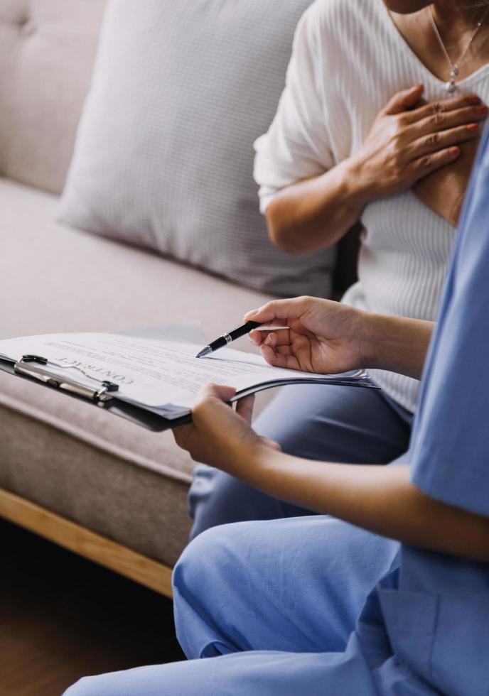 Homecare nursing service and elderly people cardiology healthcare. Close up of young hispanic female doctor nurse check mature caucasian man patient heartbeat using stethoscope during visit photo