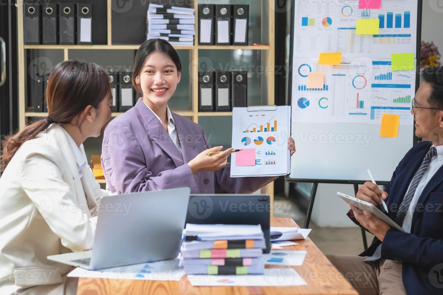 Asian business team consists of marketing staff. accountant and financial officer Help each other analyze company profits using tablets. calculator Laptop computers, graph paper, and corporate pens. photo