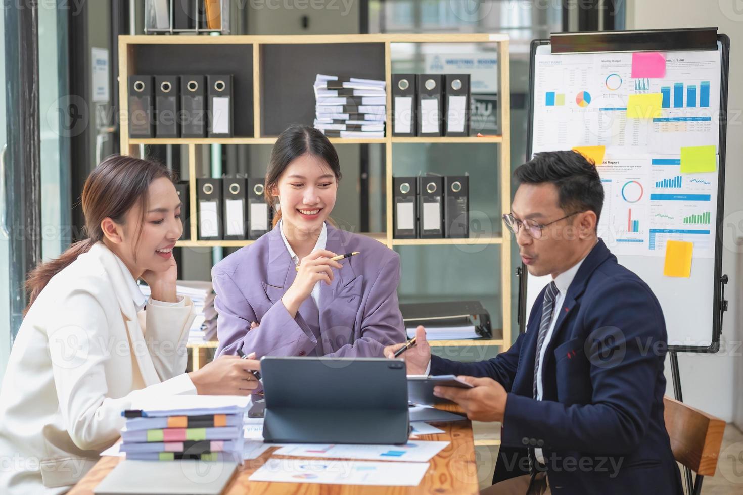 Asian business team consists of marketing staff. accountant and financial officer Help each other analyze company profits using tablets. calculator Laptop computers, graph paper, and corporate pens. photo