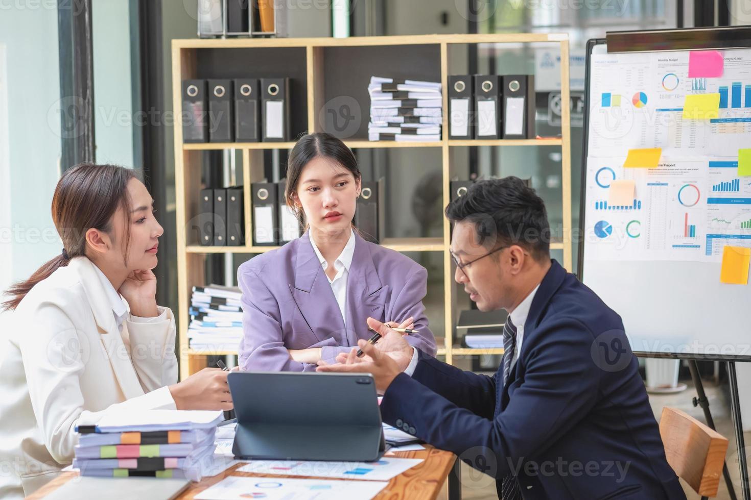 Asian business team consists of marketing staff. accountant and financial officer Help each other analyze company profits using tablets. calculator Laptop computers, graph paper, and corporate pens. photo