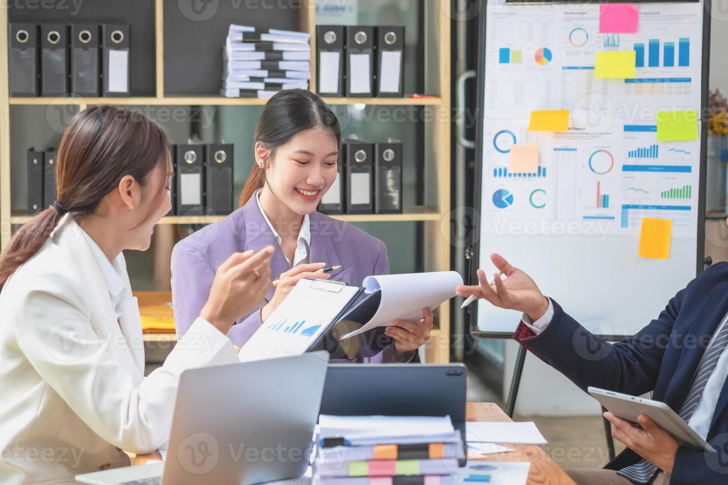 Asian business team consists of marketing staff. accountant and financial officer Help each other analyze company profits using tablets. calculator Laptop computers, graph paper, and corporate pens. photo