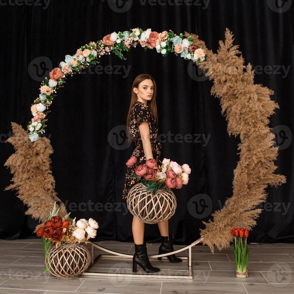 Beautiful woman posing at circle of deadwood in dress with flower print photo