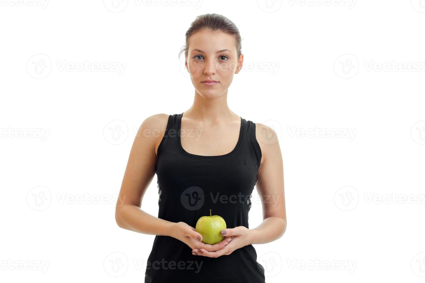 cute young girl in the black shirt looks straight and holding a Green Apple close-up photo