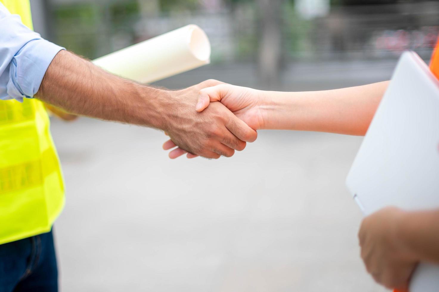 Two engineer shaking hands with deals and success agreement at construction site. Architect and worker handshaking on construction site. photo
