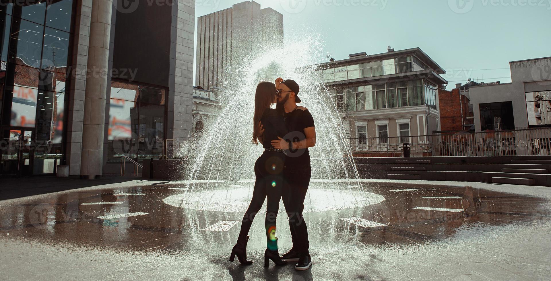 Glamour young couple hugs at the street fountain photo