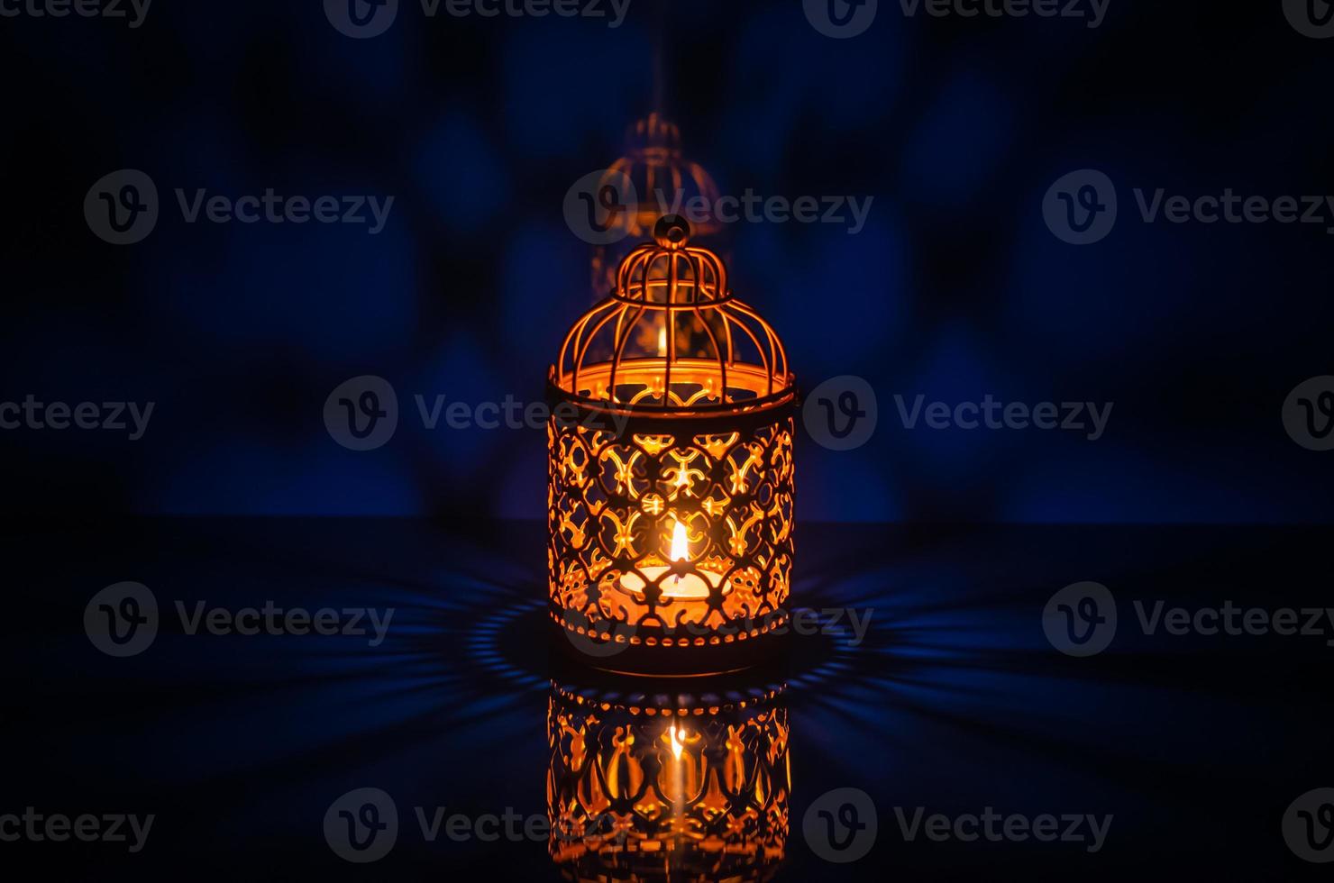 Selective focus of golden lantern with reflection from blue background for the Muslim feast of the holy month of Ramadan Kareem. photo