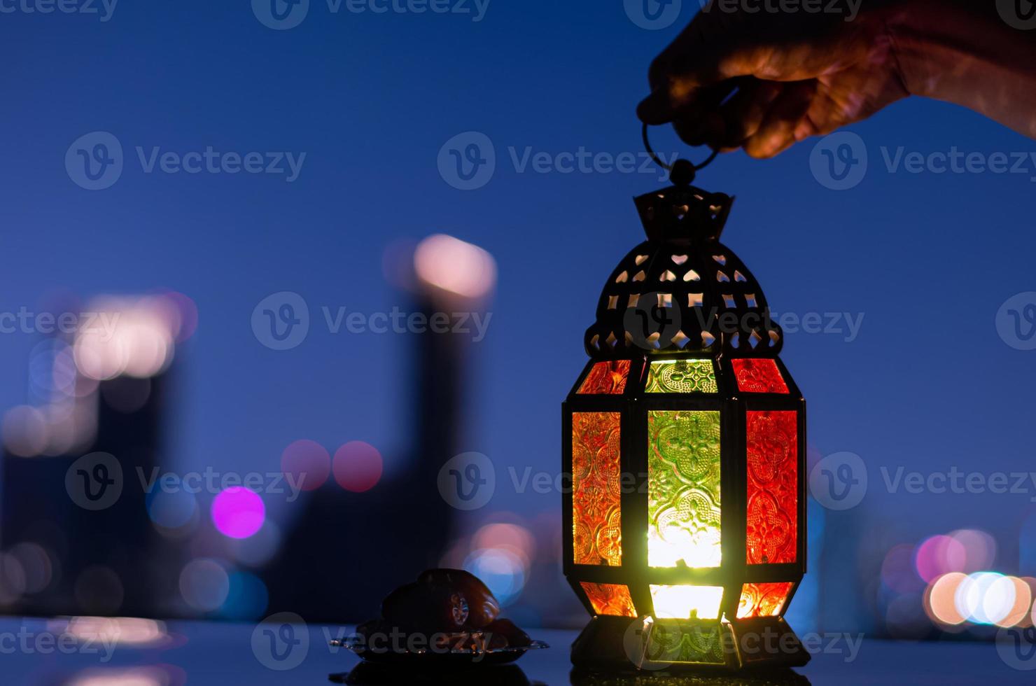 Lantern and small plate of dates fruit with city background for the Muslim feast of the holy month of Ramadan Kareem. photo