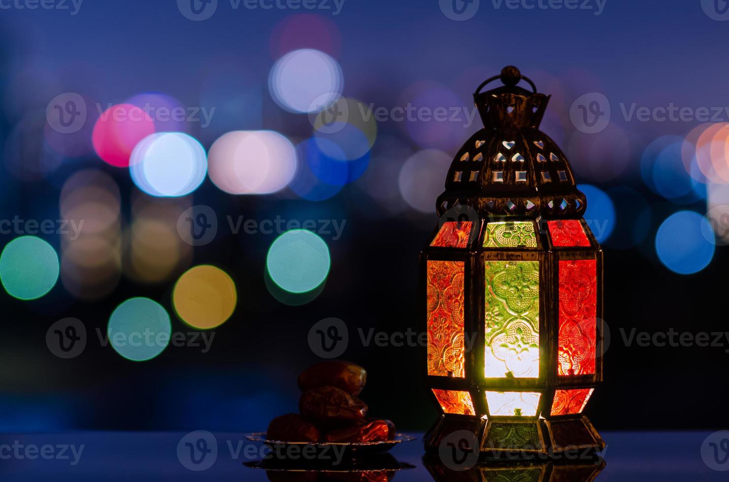 linterna y plato pequeño de dátiles con cielo nocturno y fondo claro de la ciudad para la fiesta musulmana del mes sagrado del ramadán kareem. foto