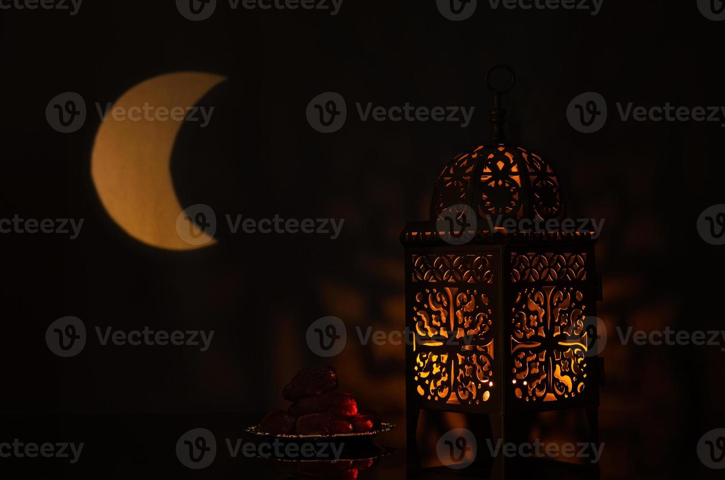 Lantern and small plate of dates fruit with moon shape from light on background for the Muslim feast of the holy month of Ramadan Kareem. photo