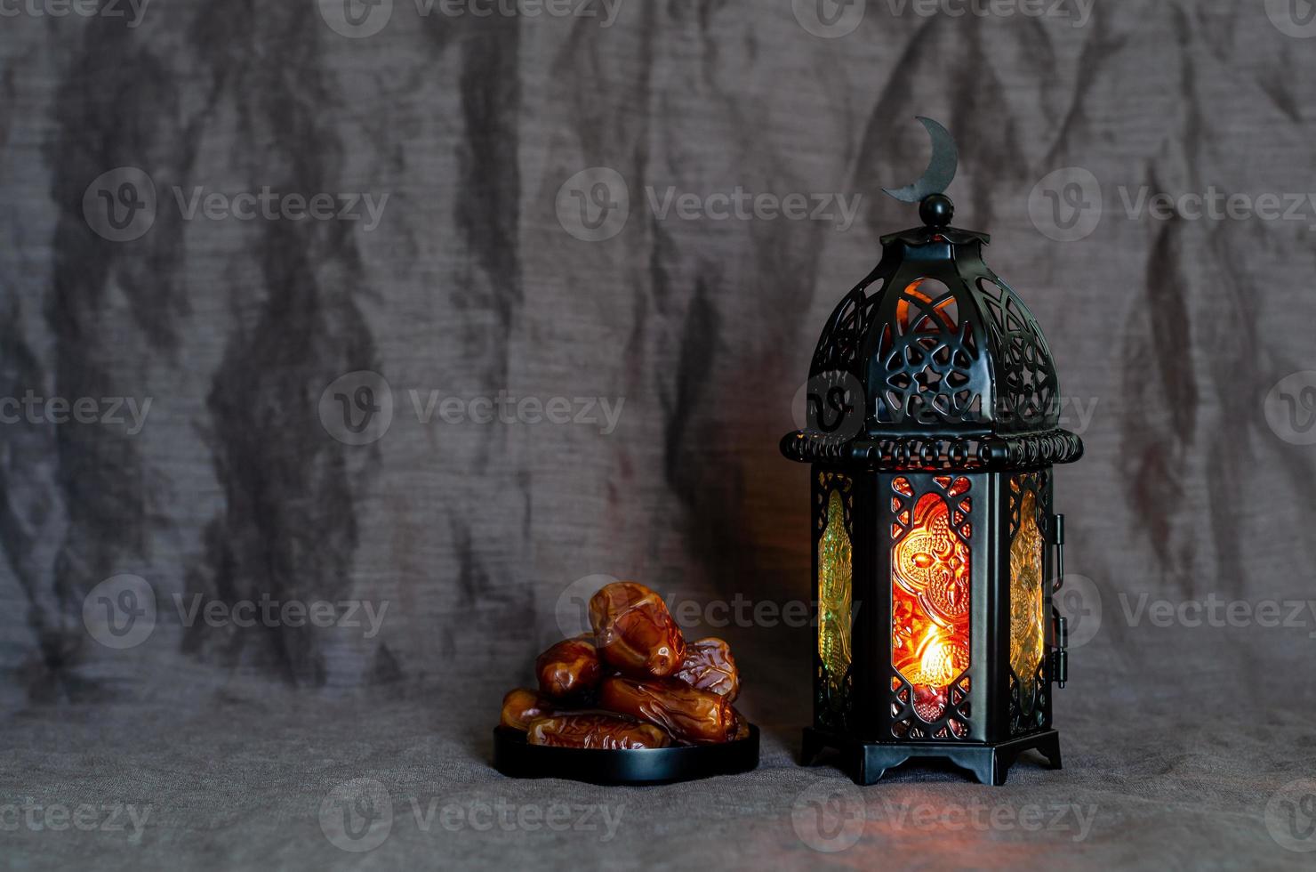 Black lantern and dates fruit on dark cloth background for the Muslim feast of the holy month of Ramadan Kareem. photo