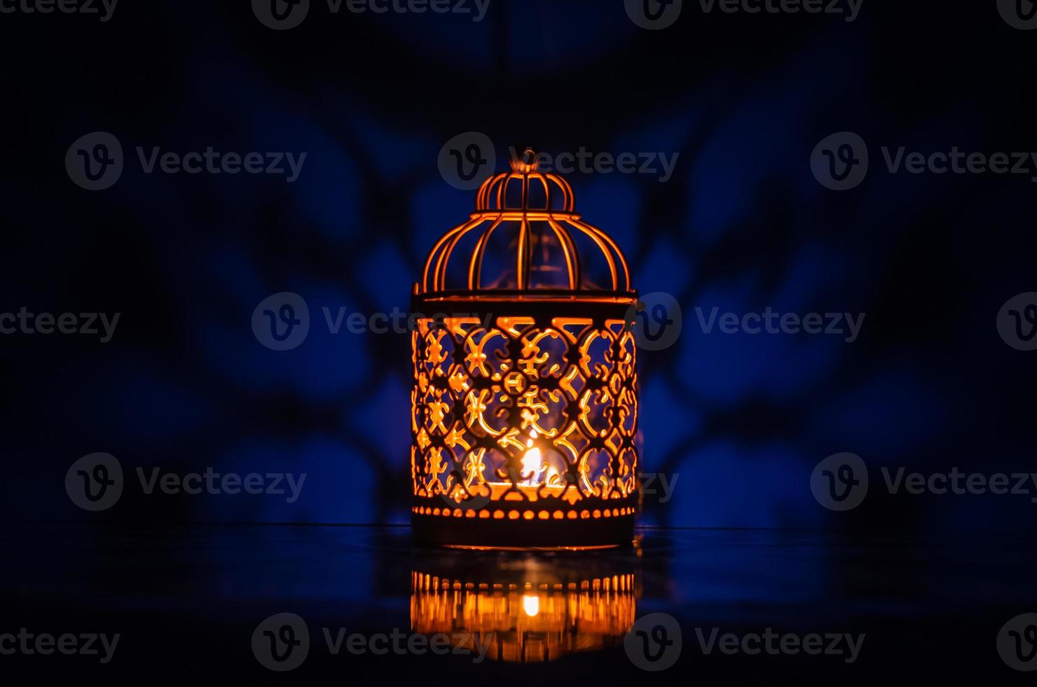 Selective focus of golden lantern with reflection from blue background for the Muslim feast of the holy month of Ramadan Kareem. photo