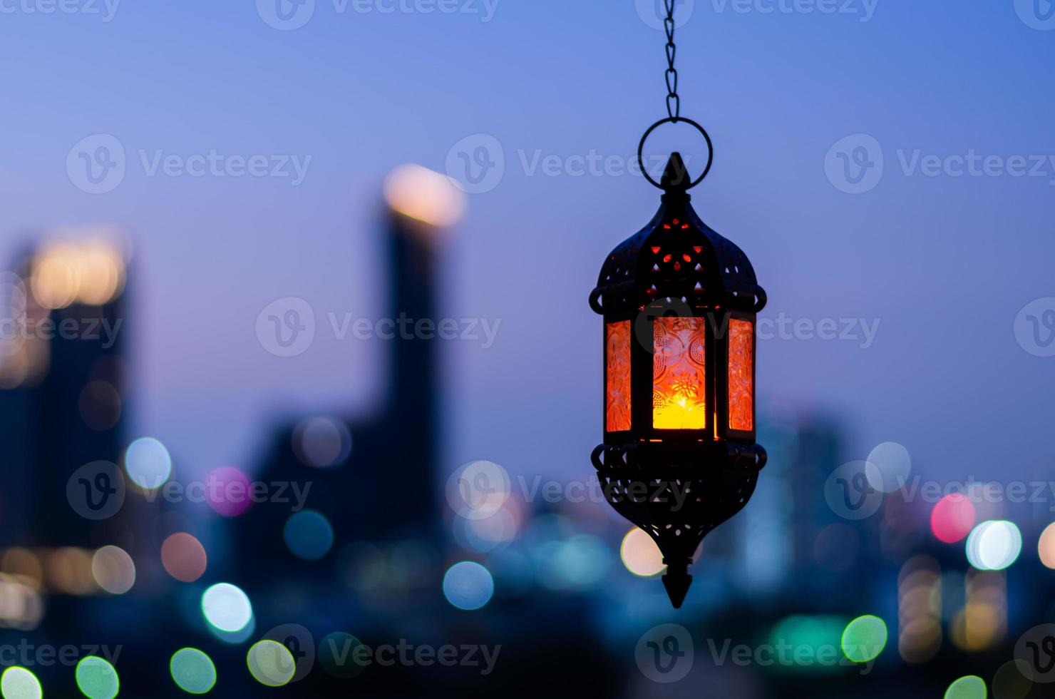 Hanging lantern with night sky and city bokeh light background for the Muslim feast of the holy month of Ramadan Kareem. photo