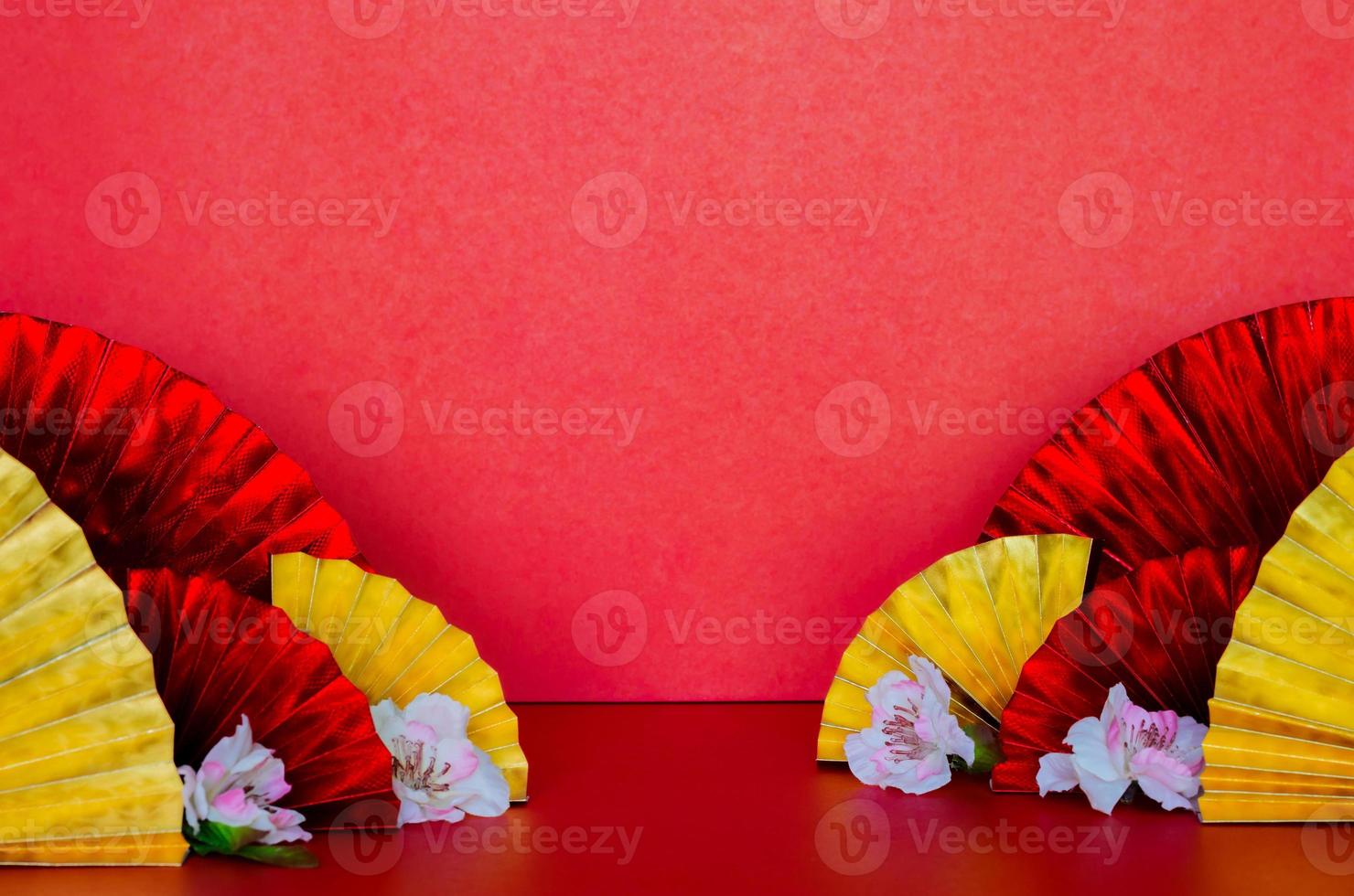 enfoque selectivo en algunos abanicos orientales dorados y rojos con flor de melocotón sobre fondo rojo para el concepto de año nuevo chino. foto