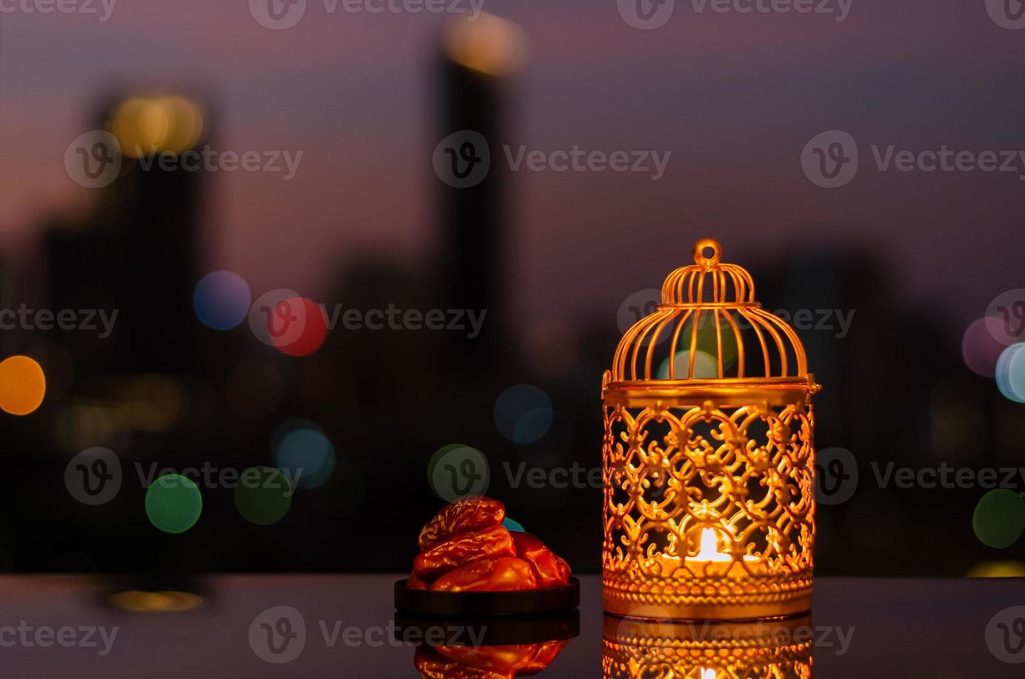 Golden lantern and dates fruit with dusk sky and city bokeh light background for the Muslim feast of the holy month of Ramadan Kareem. photo