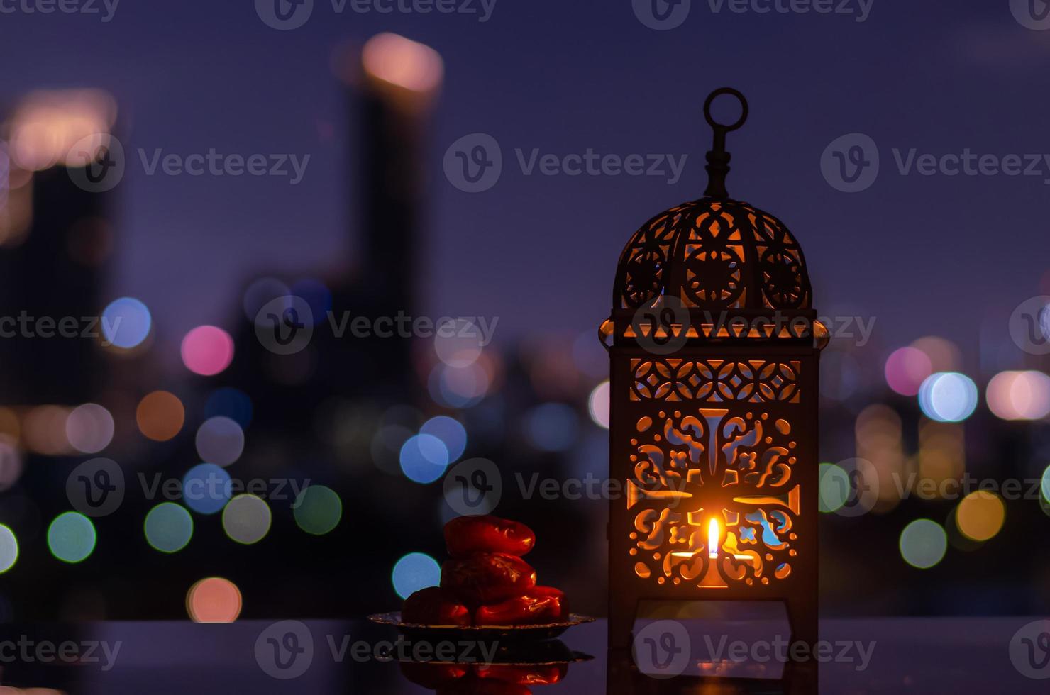 linterna y plato pequeño de dátiles con cielo nocturno y fondo claro de la ciudad para la fiesta musulmana del mes sagrado del ramadán kareem. foto