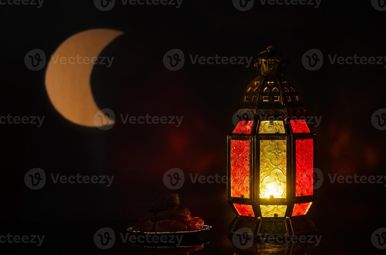 Lantern and small plate of dates fruit with moon shape from light on background for the Muslim feast of the holy month of Ramadan Kareem. photo