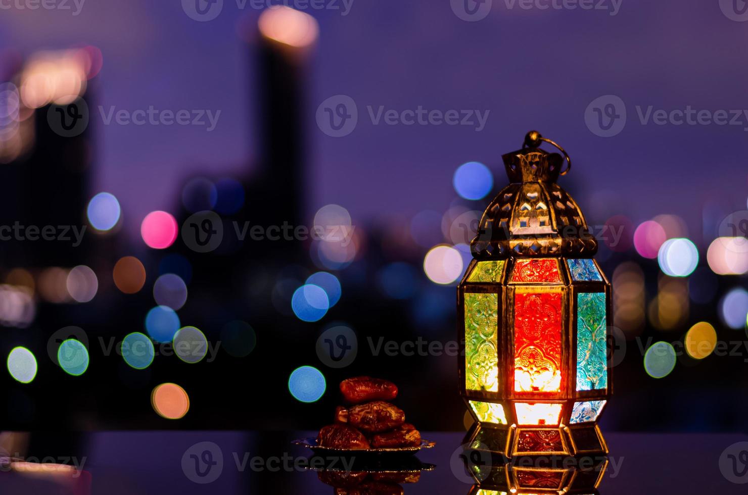 linterna y plato pequeño de dátiles con cielo nocturno y fondo claro de la ciudad para la fiesta musulmana del mes sagrado del ramadán kareem. foto
