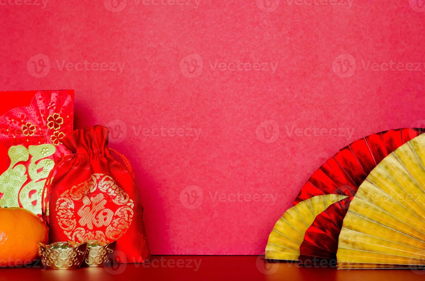 Selective on Red bag word mean wealth with envelope packets or ang bao word means wealth, ingots and orange with golden and red oriental fans on red background for Chinese new year concept. photo