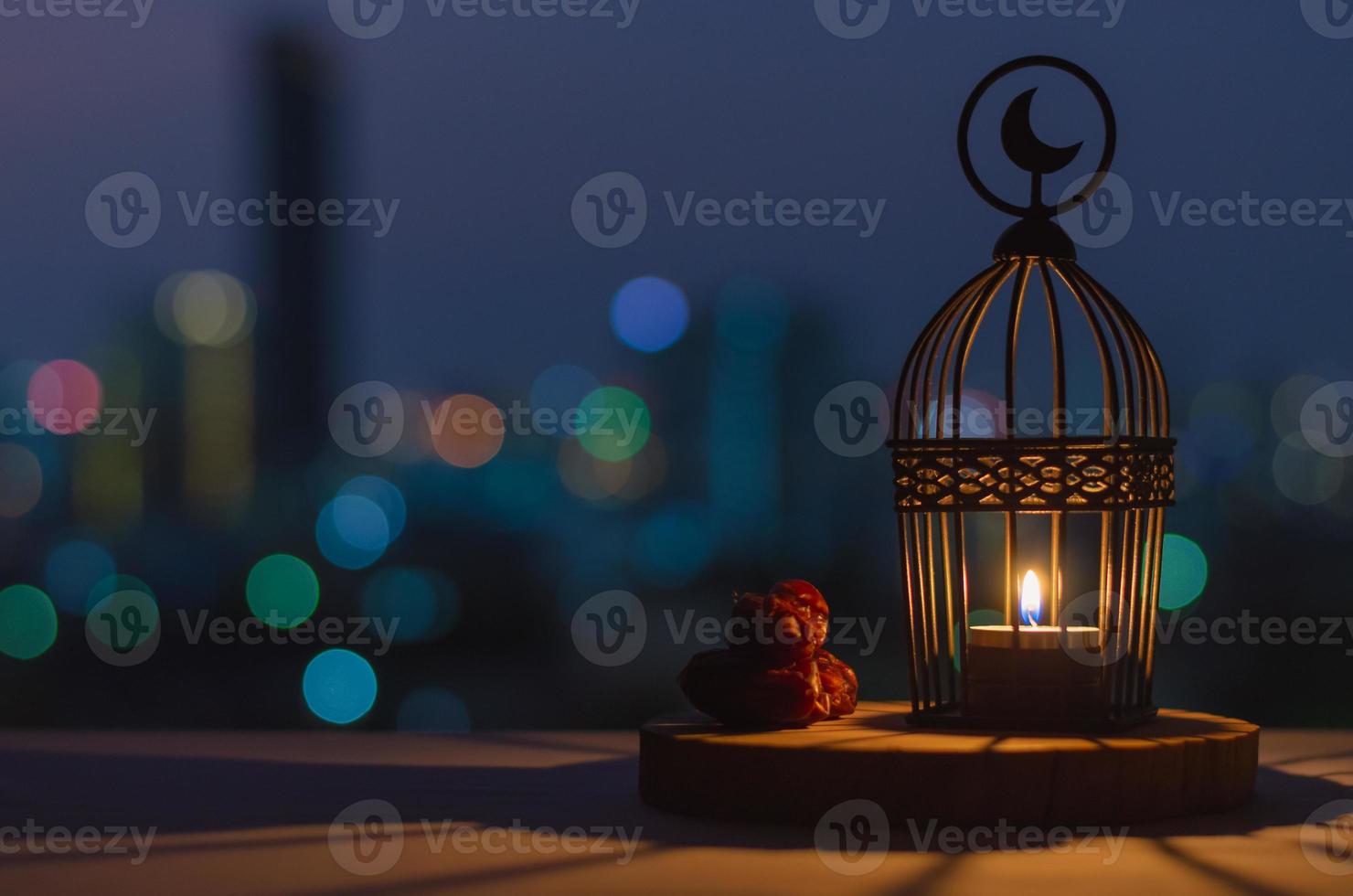 Lantern that have moon symbol on top and dates fruit put on wooden tray with colorful city bokeh lights for the Muslim feast of the holy month of Ramadan Kareem. photo