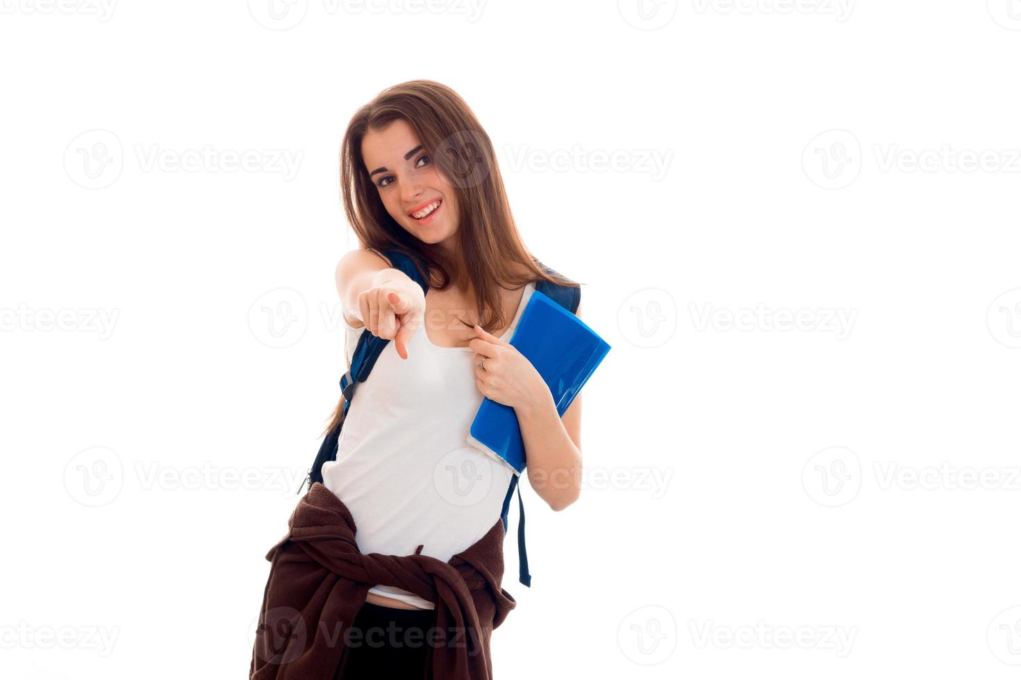 young girl in white shirt and with a rucksack on shoulder stretches arm forward and smiling photo