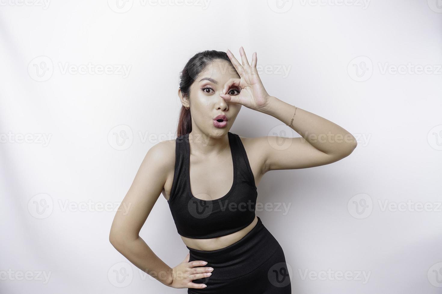 una mujer asiática deportiva emocionada que usa ropa deportiva está dando un gesto de mano bien aislado por un fondo blanco foto