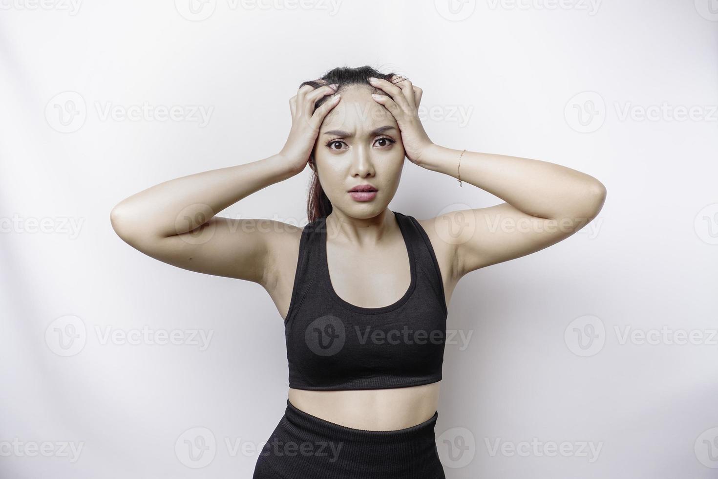 A portrait of an sporty Asian woman wearing a sportswear isolated by white background looks depressed photo
