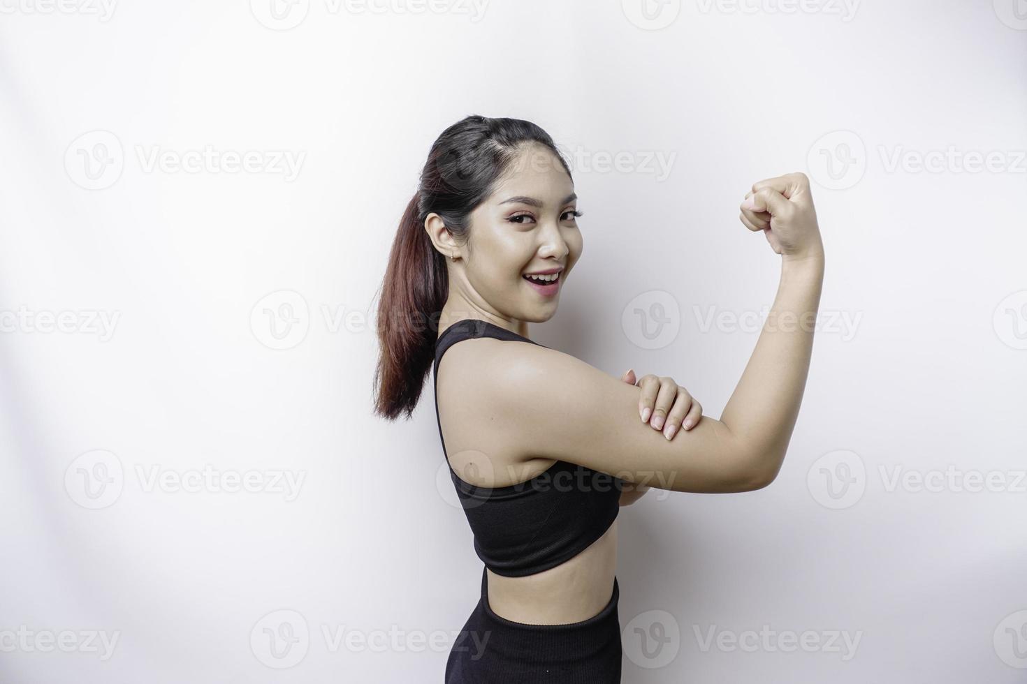 emocionada mujer deportiva asiática con ropa deportiva que muestra un gesto fuerte levantando los brazos y los músculos sonriendo con orgullo foto