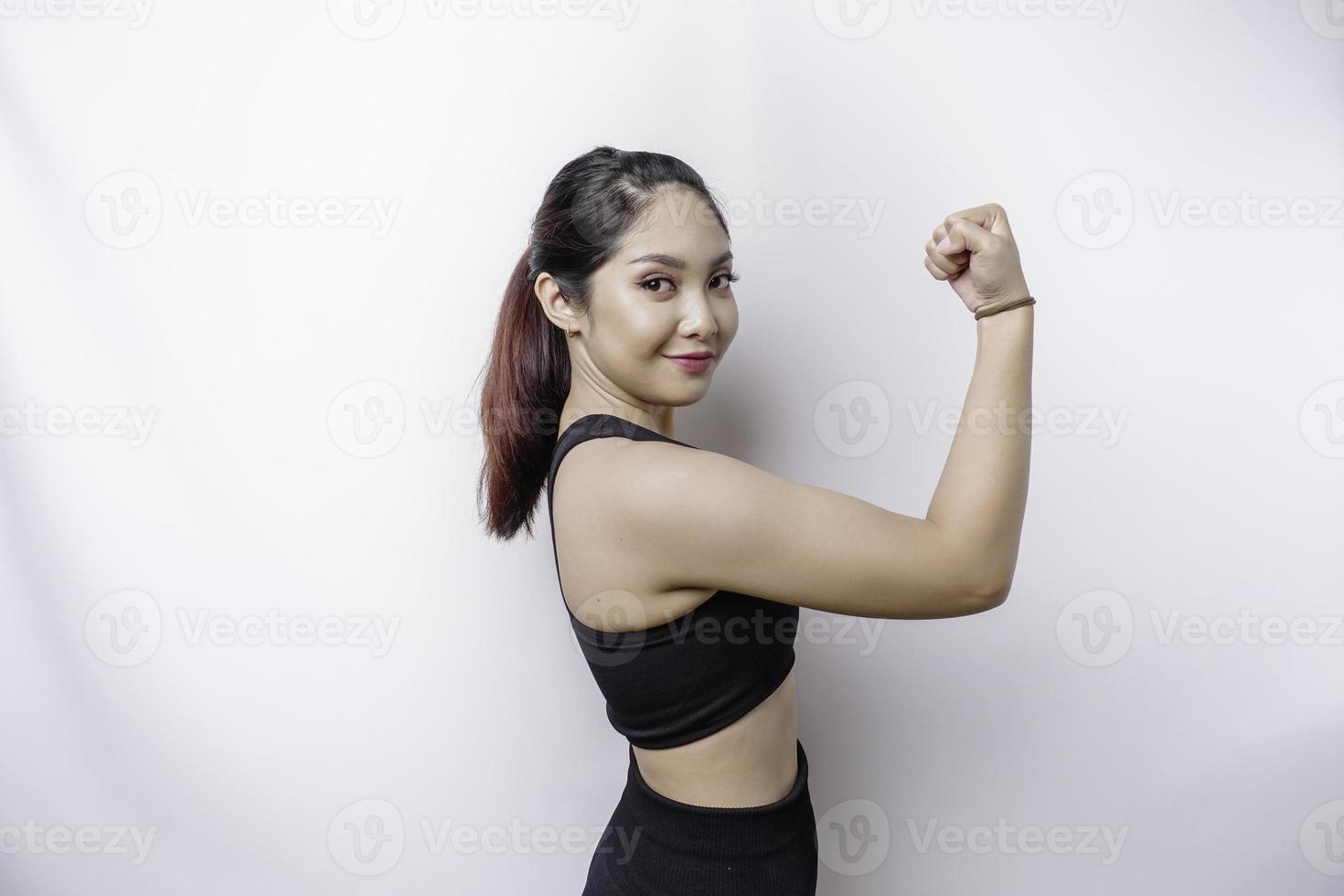 emocionada mujer deportiva asiática con ropa deportiva que muestra un gesto fuerte levantando los brazos y los músculos sonriendo con orgullo foto