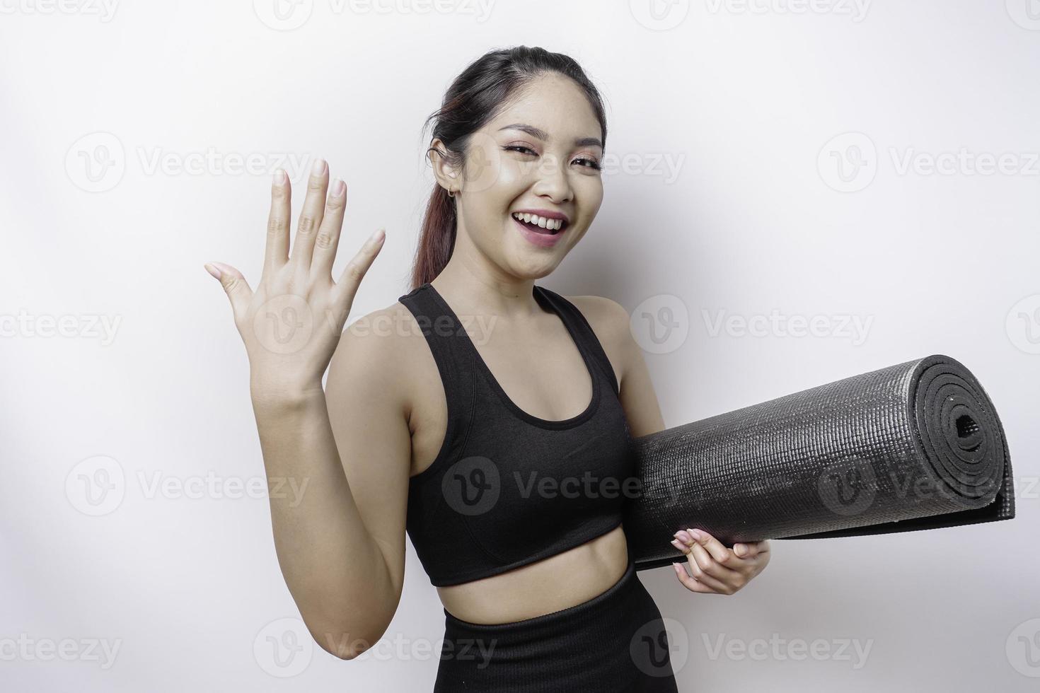 Young Asian beautiful sporty woman carrying yoga mat, isolated white background inviting to join with hand. Happy that you came photo