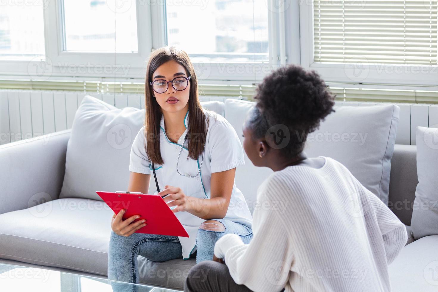 healthcare and medicine concept - serious doctor with clipboard and patient in hospital. View of a Young doctor showing results on tablet to patient photo