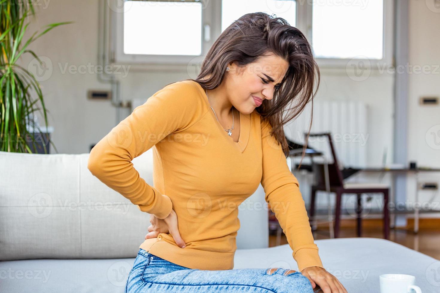 dolor de espalda. primer plano de una mujer joven que tiene dolor espinal o renal, dolor de espalda. niña que sufre de sensación dolorosa, dolor muscular o nervioso, con las manos en el cuerpo. concepto de problema de salud. foto