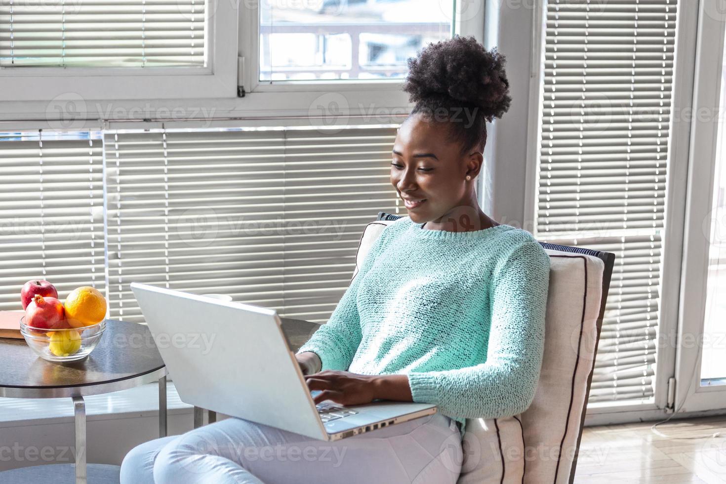 Happy casual beautiful woman working on a laptop sitting on the sofa in the house. From early morning I am checking my mailbox photo