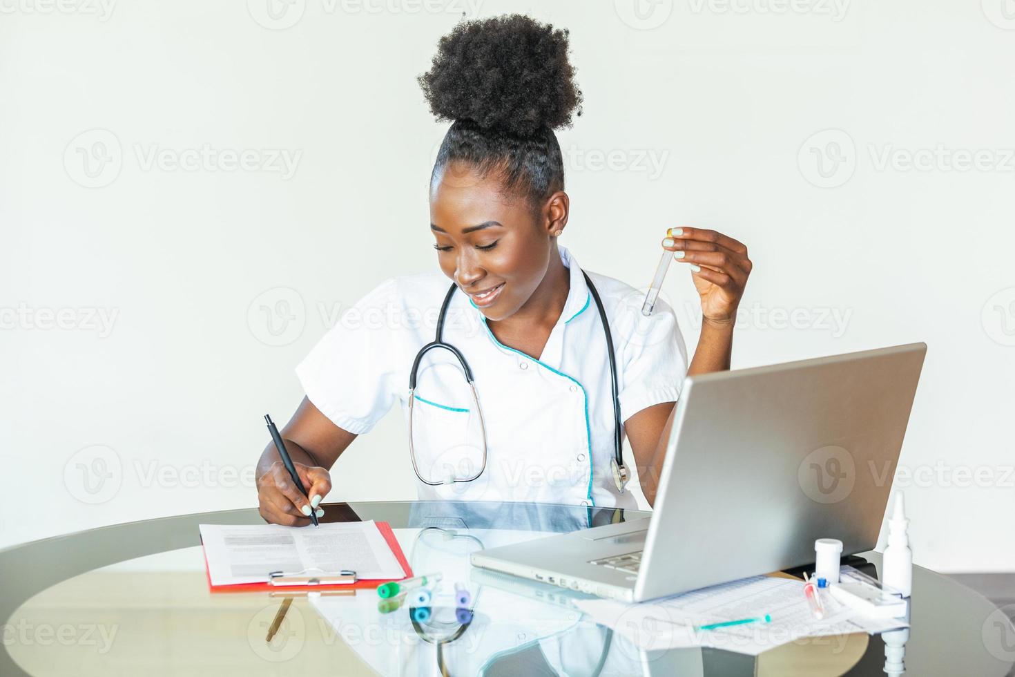 Female doctor in white coat holding blood test tubes in hands while wrapped up in work at modern lab. Female life science professional holding glass cuvette. Healthcare and biotechnology concept. photo