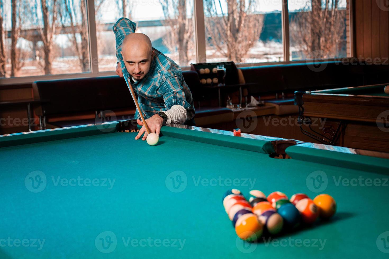 chico concentrándose en romper la pirámide de bolas en el ángulo de la mesa foto