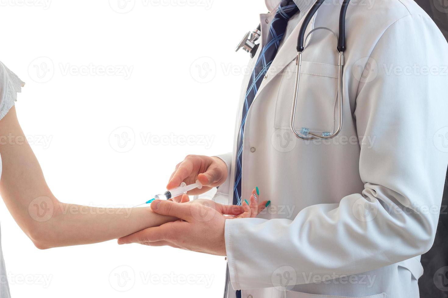 un médico con una bata blanca inyecta el primer plano de la mano de una niña foto