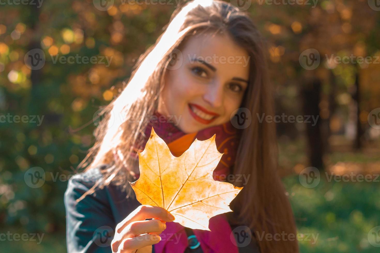 beautiful girl smiling and holding a maple leaf in his hand photo