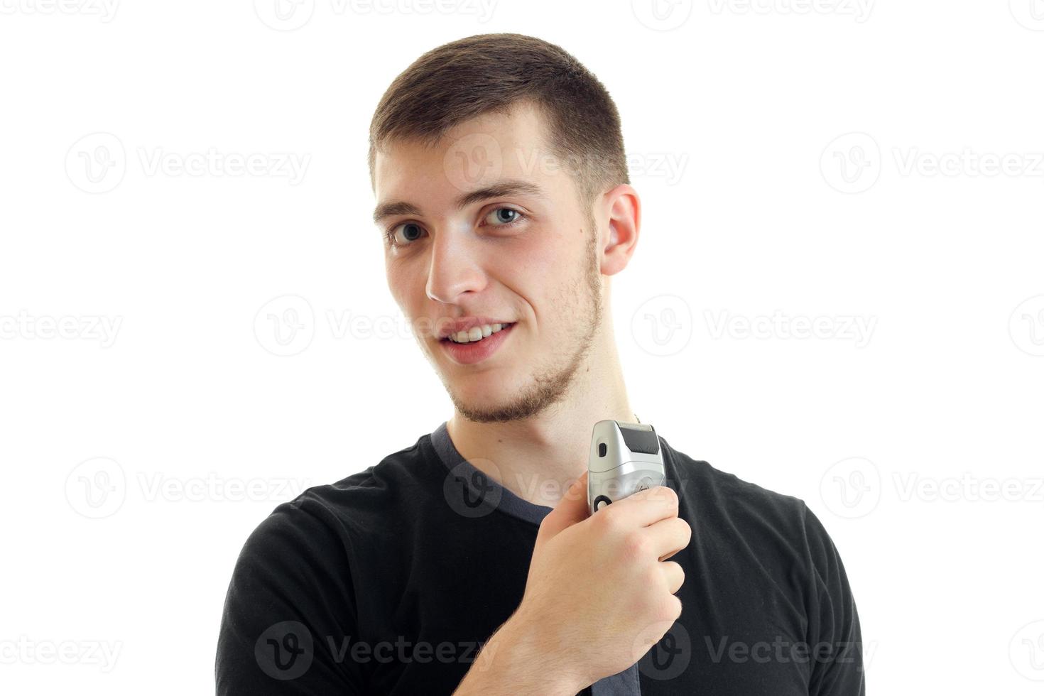 charming portrait of a young smiling guy with shaving machine in hand photo